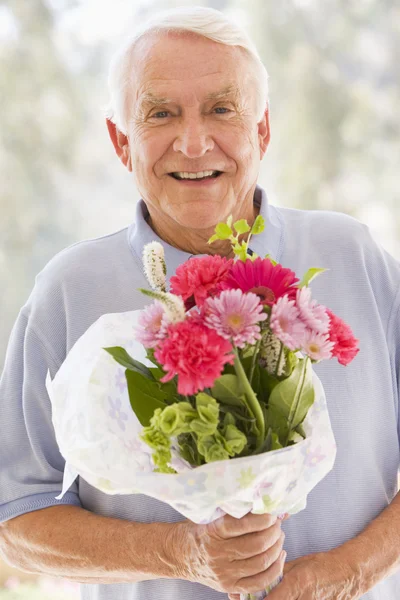 Mężczyzna trzyma kwiaty i uśmiechając się — Zdjęcie stockowe
