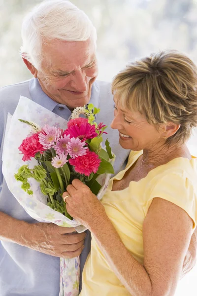 Manžel dává ženě květiny a usmívá se — Stock fotografie