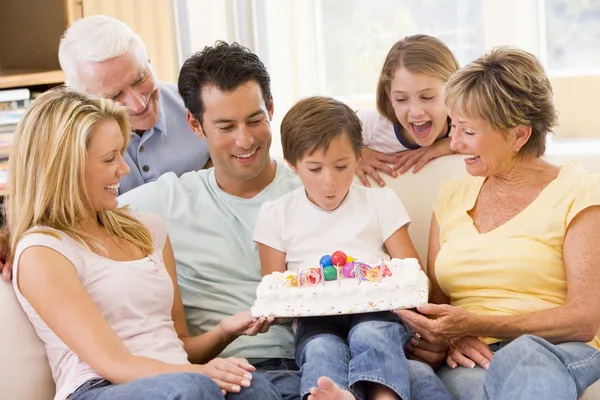 Familie in woonkamer lachend met jonge jongen uitblazen van de kaarsen — Stockfoto