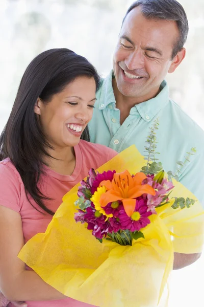 Муж и жена держат цветы и улыбаются — стоковое фото