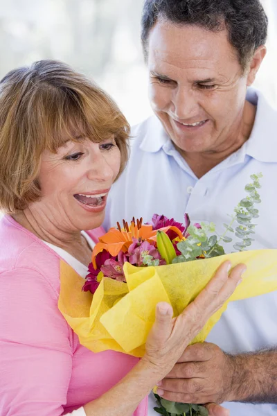 Mąż i żona trzyma kwiaty i uśmiechając się — Zdjęcie stockowe
