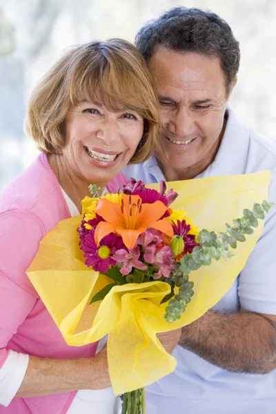 夫と妻の花を保持していると笑みを浮かべて — ストック写真