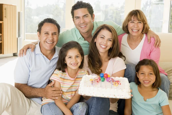 Семья в гостиной с тортом улыбается — стоковое фото