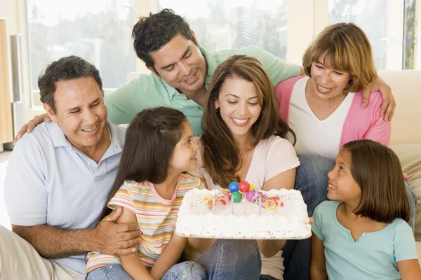 Family in living room with cake smiling — Stock Photo, Image