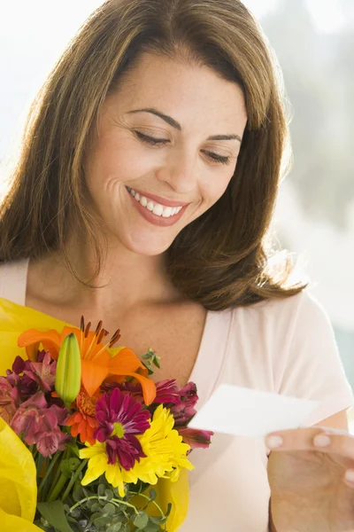 女性の花を保持していると笑みを浮かべてノートを読む — ストック写真