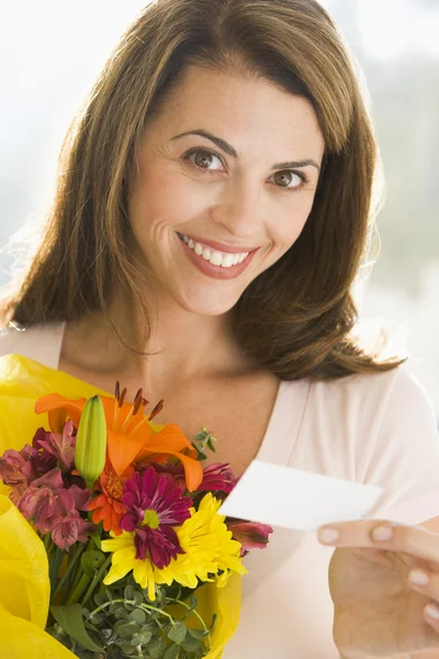 Woman holding flowers and note smiling — Stock Photo, Image