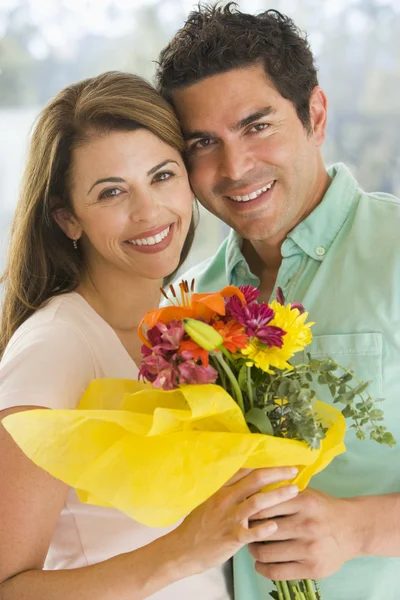 Муж и жена держат цветы и улыбаются — стоковое фото