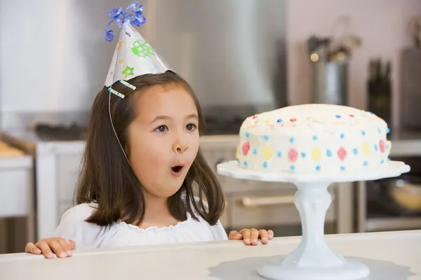 Κοπέλα Φορώντας Καπέλο Κόμμα Στο Μετρητή Κουζινών Κοιτάζοντας Κέικ — Φωτογραφία Αρχείου