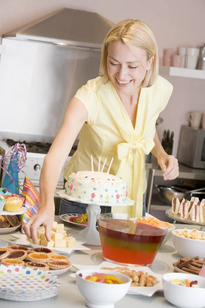 Жінка на вечірці стає терпкою з харчового столу посміхається — стокове фото