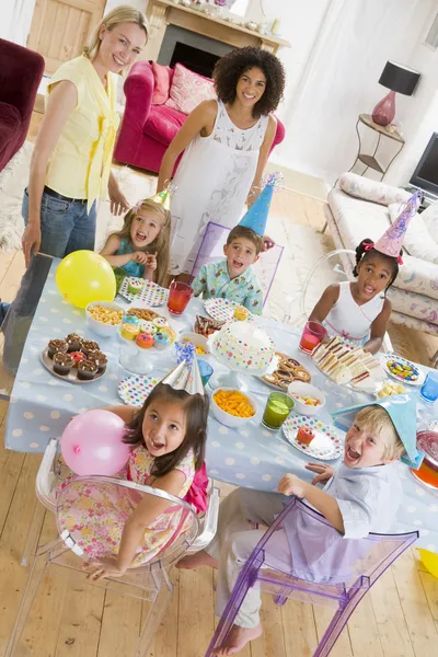 Små barn på fest med mödrar sitter vid bord med mat — Stockfoto