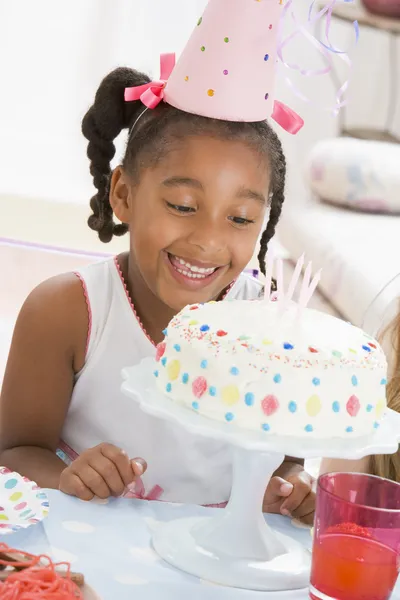ケーキの笑みを浮かべて見てパーティー帽子を着た少女 — ストック写真