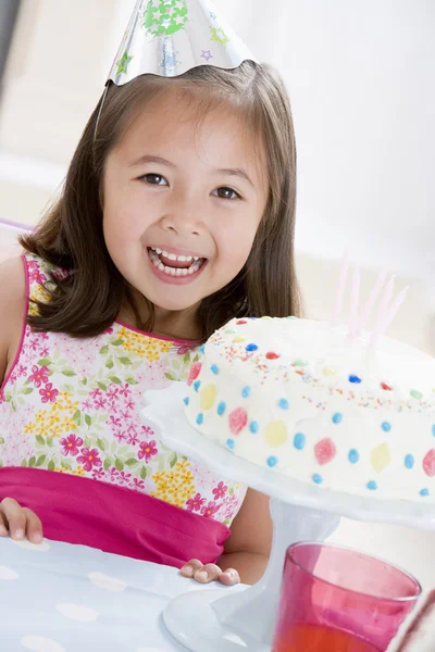 笑みを浮かべて誕生日ケーキのパーティの帽子を着ている若い女の子 — ストック写真