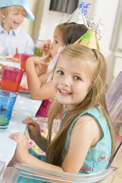 Молодая девушка на вечеринке сидит за столом с улыбкой на еде — стоковое фото