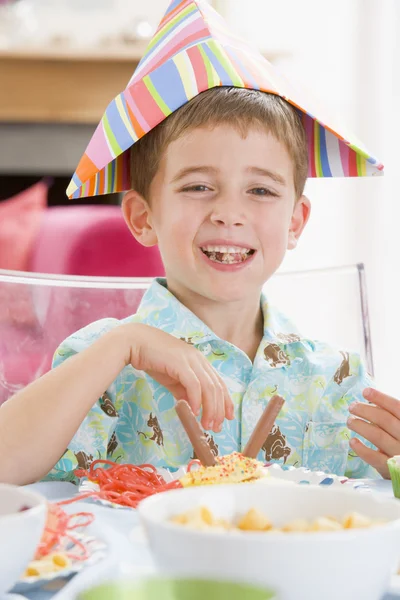 Jonge jongen op feestje zitten aan tafel met voedsel lachende — Stockfoto
