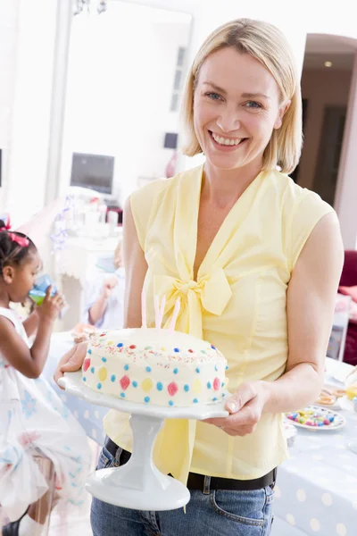 Woman at party holding birthday cake smiling — Stock Photo, Image