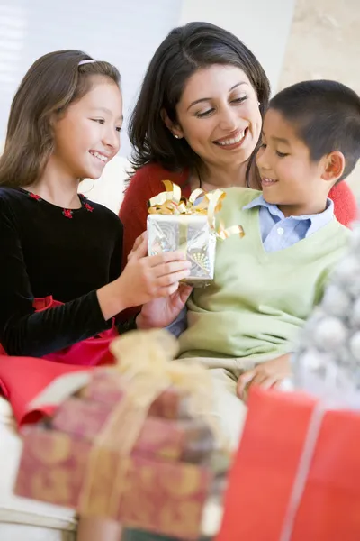 Mutter sitzt mit Sohn und Tochter und tauscht Weihnachtsgeschenke aus — Stockfoto