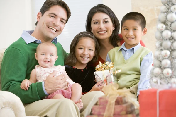 Rodina s nové rodí, seděl na pohovce, drží vánoční dárek — Stock fotografie