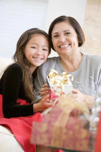Grandmother And Granddaughter Sitting On Sofa Holding A Christma — Stock Photo, Image