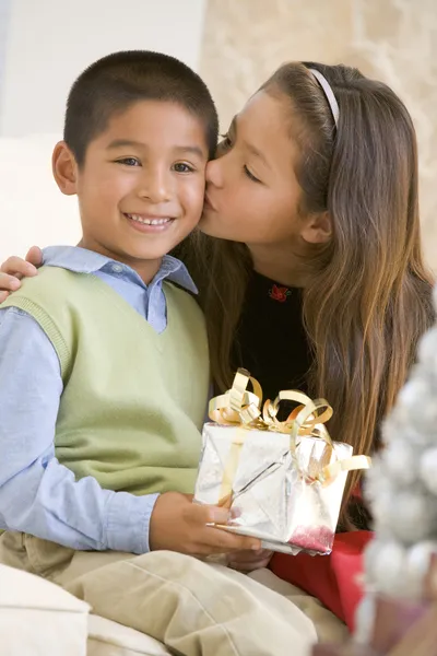 Syster ger hennes bror en julklapp och kyssa honom på — Stockfoto