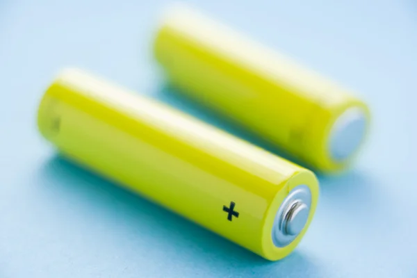 Duas baterias amarelas contra um fundo azul — Fotografia de Stock