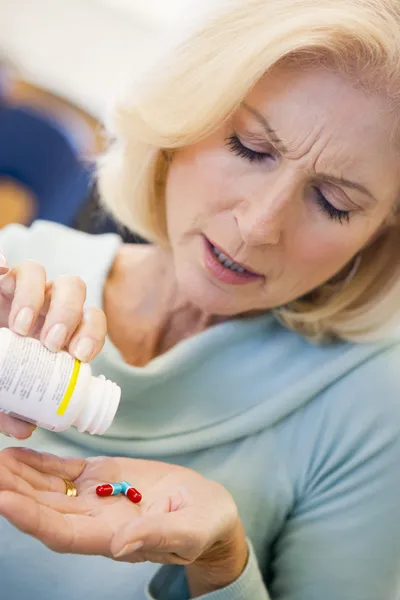 年配の女性が瓶から錠剤を注ぐ — ストック写真