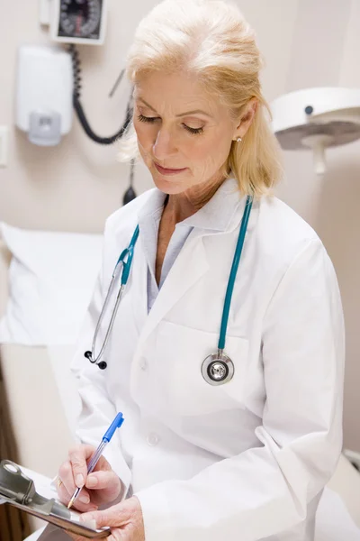 Orta yaşlı kadın doktor bir panoda yazıyor — Stok fotoğraf