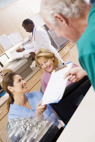 Verpleegkundigen wordt overhandigd een Klembord bij de receptie in een hospi — Stockfoto