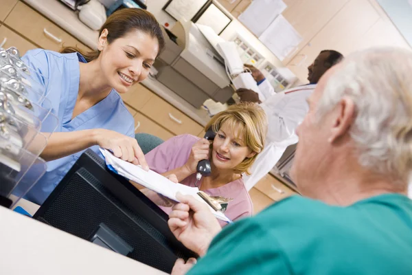 Krankenschwestern diskutieren ein Klemmbrett an der Rezeption in einem Krankenhaus — Stockfoto