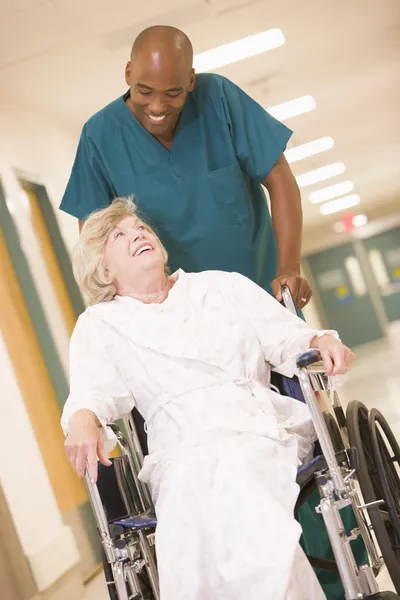 Порядок толкает пожилую женщину в инвалидном кресле в больницу — стоковое фото