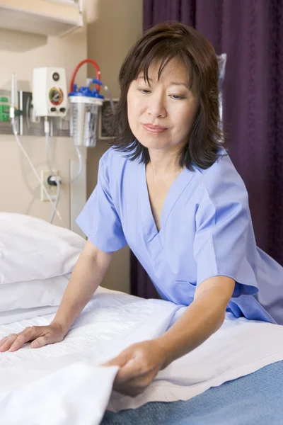 一名护士在医院病房里做一张床 — 图库照片
