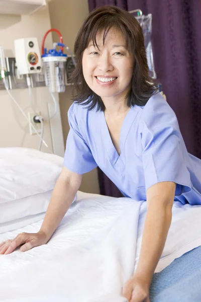 Медсестра, застилающая кровать в палате больницы — стоковое фото