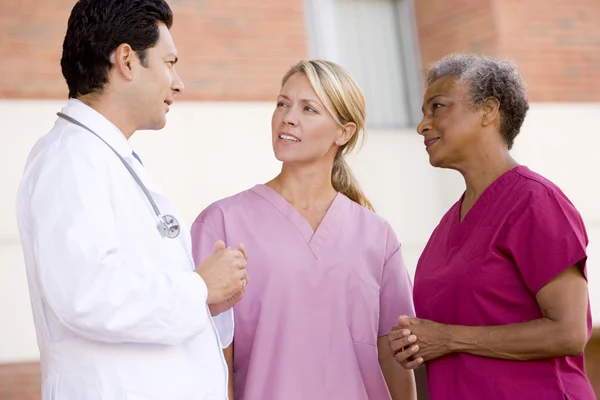 Arzt und Krankenschwestern stehen vor einem Krankenhaus — Stockfoto