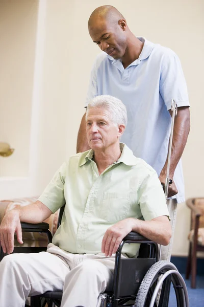 Pielęgniarka pchania człowieka na wózku inwalidzkim — Zdjęcie stockowe