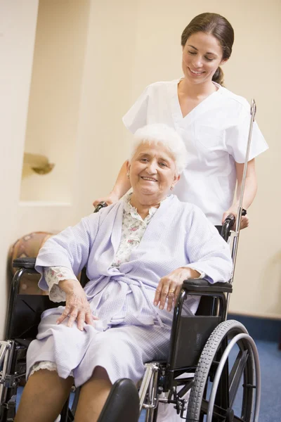 Медсестра толкает пожилую женщину в инвалидном кресле — стоковое фото