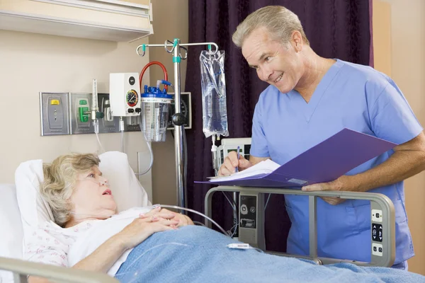 Доктор делает заметки о пациентке пожилого возраста — стоковое фото