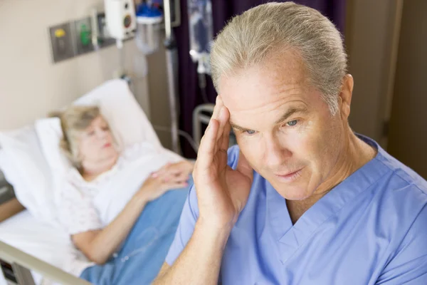 Medico in piedi nella stanza dei pazienti, guardando frustrato — Foto Stock