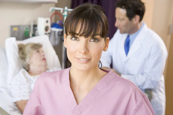 Sjuksköterska stående i sjukhussal, läkare pratar med patienten — Stockfoto