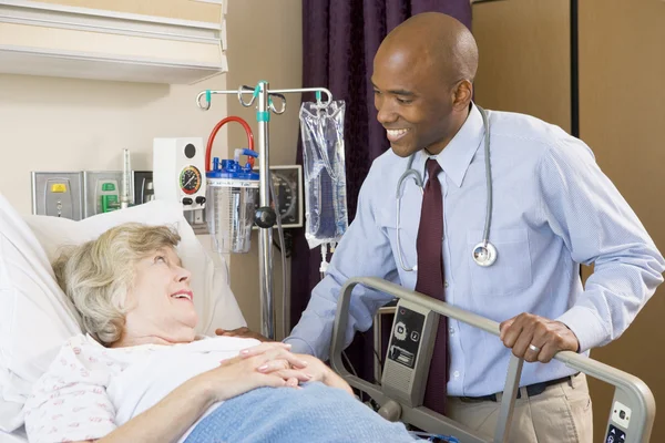 Врач разговаривает со старшей женщиной, лежащей на больничной койке — стоковое фото
