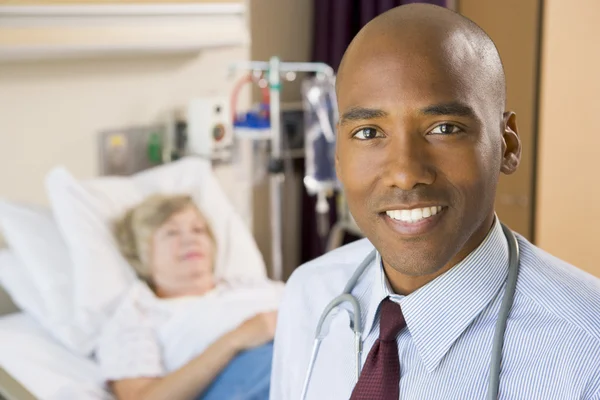 Доктор улыбается, стоя в больничной палате — стоковое фото