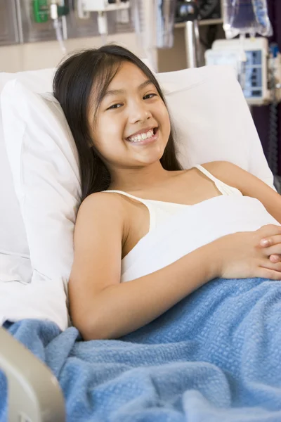 Chica joven sonriendo, acostada en la cama del hospital — Foto de Stock