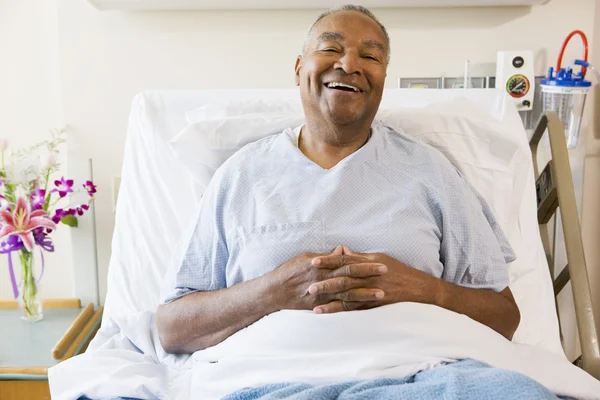 Ανώτερος άνθρωπος που κάθεται στο κρεβάτι του στο νοσοκομείο, χαμογελώντας — Φωτογραφία Αρχείου