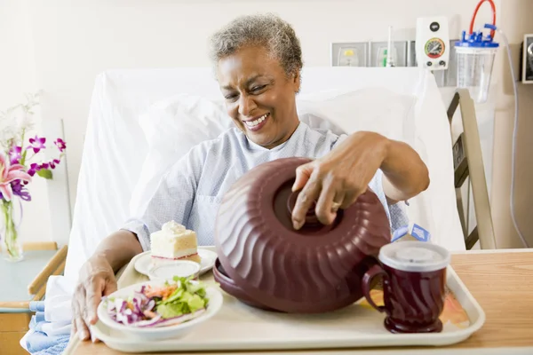 Mujer mayor sentada en la cama del hospital con una bandeja de comida — Foto de Stock