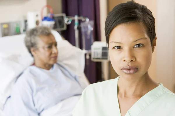 Sjuksköterska stående i patienter rummet tittar allvarligt — Stockfoto