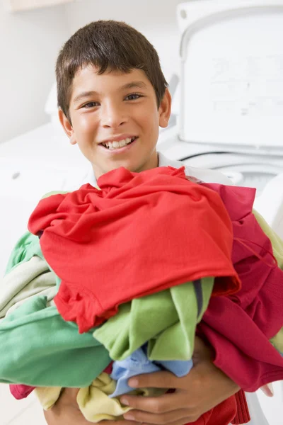 Çamaşırhane yığını tutan genç çocuk — Stok fotoğraf