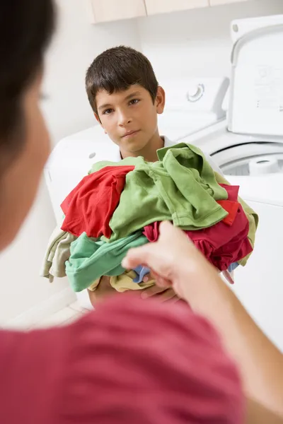 Giovane ragazzo holding un mucchio di lavanderia — Foto Stock
