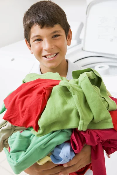 Çamaşırhane yığını tutan genç çocuk — Stok fotoğraf