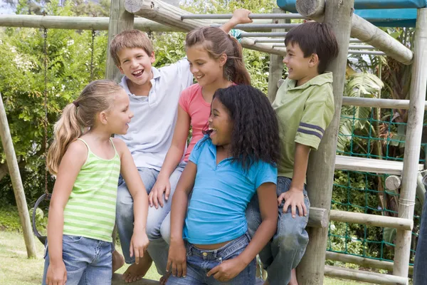 П'ять молодих друзів на дитячому майданчику посміхаються — стокове фото
