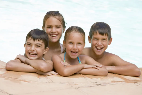 Vier junge Freunde im Schwimmbad lächeln — Stockfoto