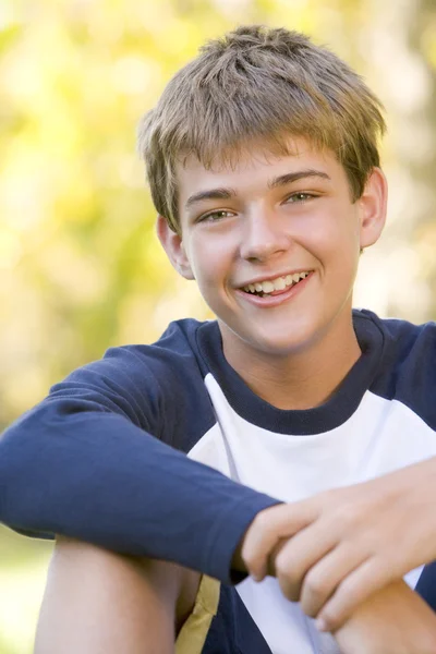 Açık Havada Gülümseyerek Oturan Genç Çocuk — Stok fotoğraf