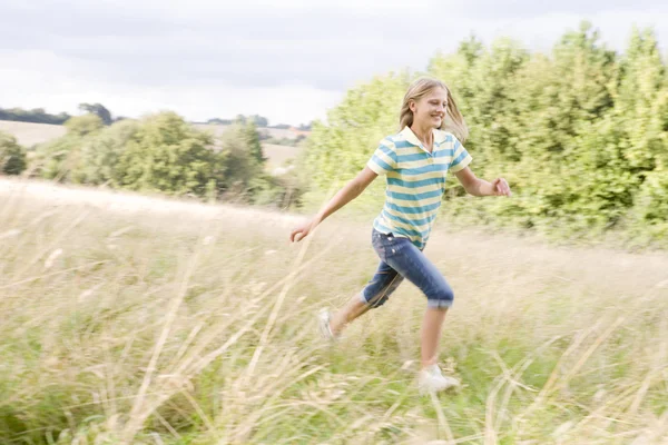 Menina correndo em um campo sorrindo — Fotografia de Stock